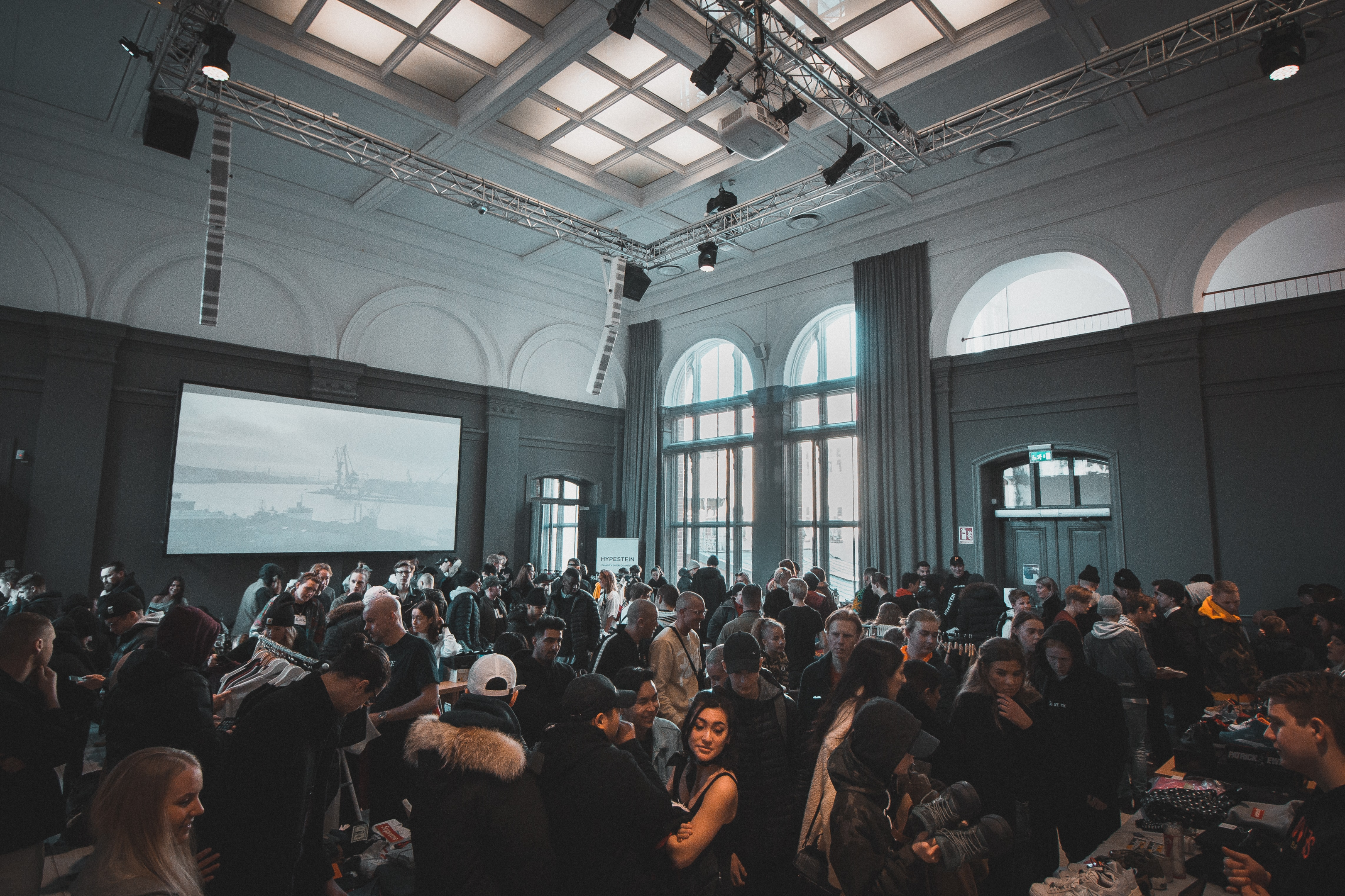 Face to Face Events Back on Track | photo of a small crowd gathered in an enclosed lounge. | Link: https://images.unsplash.com/photo-1531058020387-3be344556be6?ixlib=rb-1.2.1&ixid=MnwxMjA3fDB8MHxwaG90by1wYWdlfHx8fGVufDB8fHx8&auto=format&fit=crop&w=870&q=80