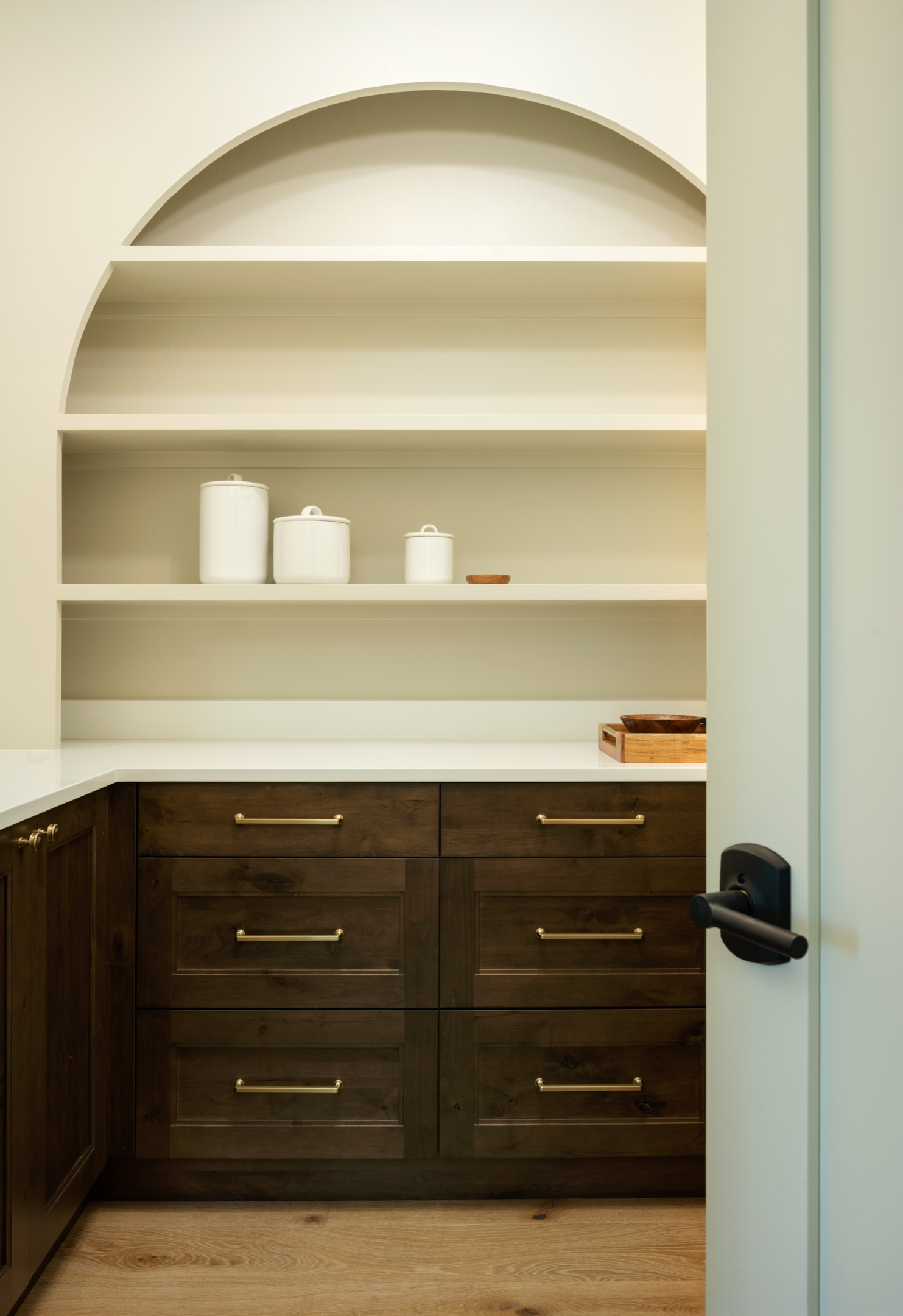 dark brown pantry drawers with arched shelving 