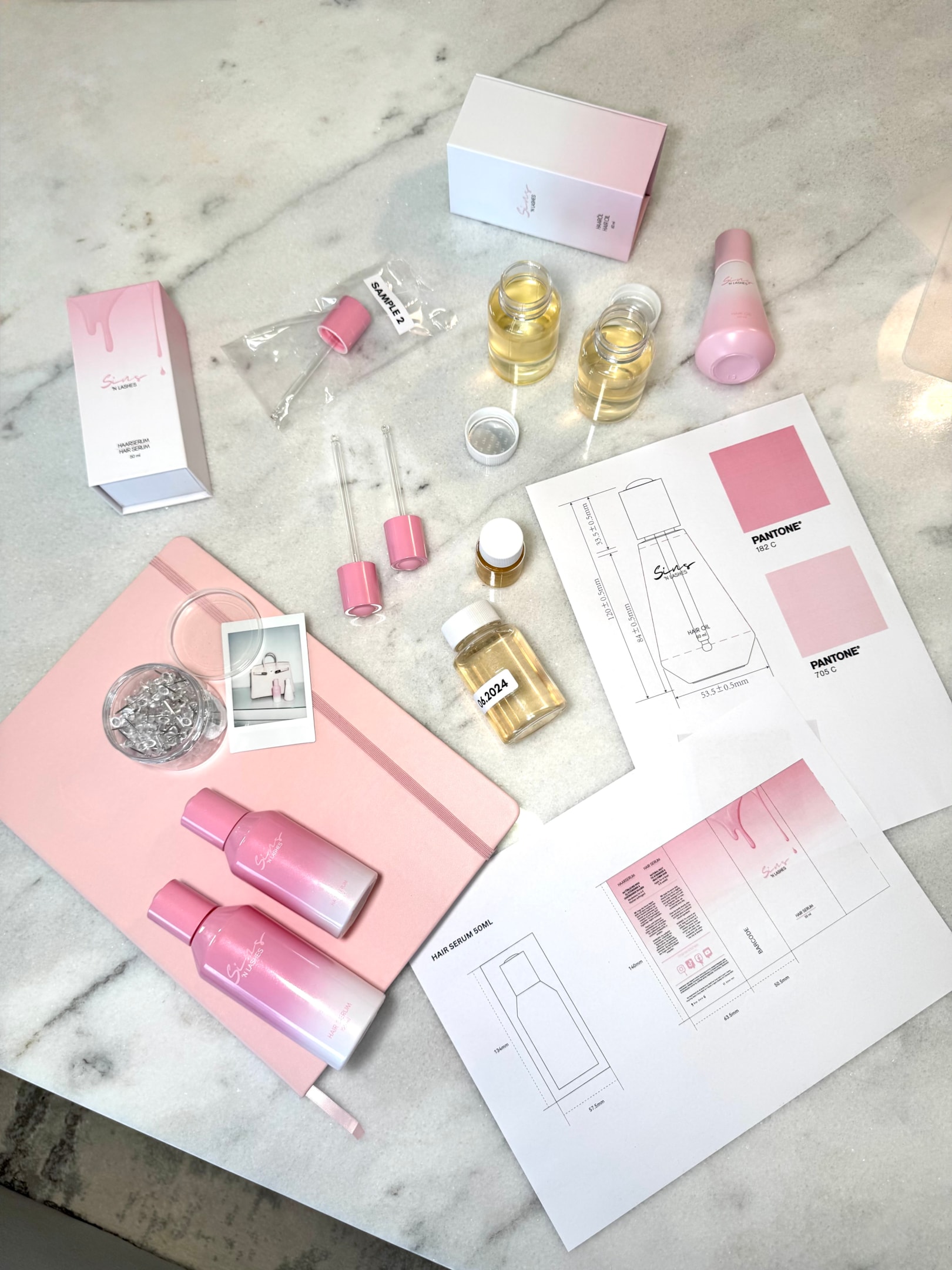 Flatlay mit Sins ’N Lashes Haircare-Produkten, Pipetten, Musterölen, Verpackungsentwürfen und Pantone-Farbkarten – Einblicke in die Produktentwicklung und das hochwertige Packaging-Design der Marke.