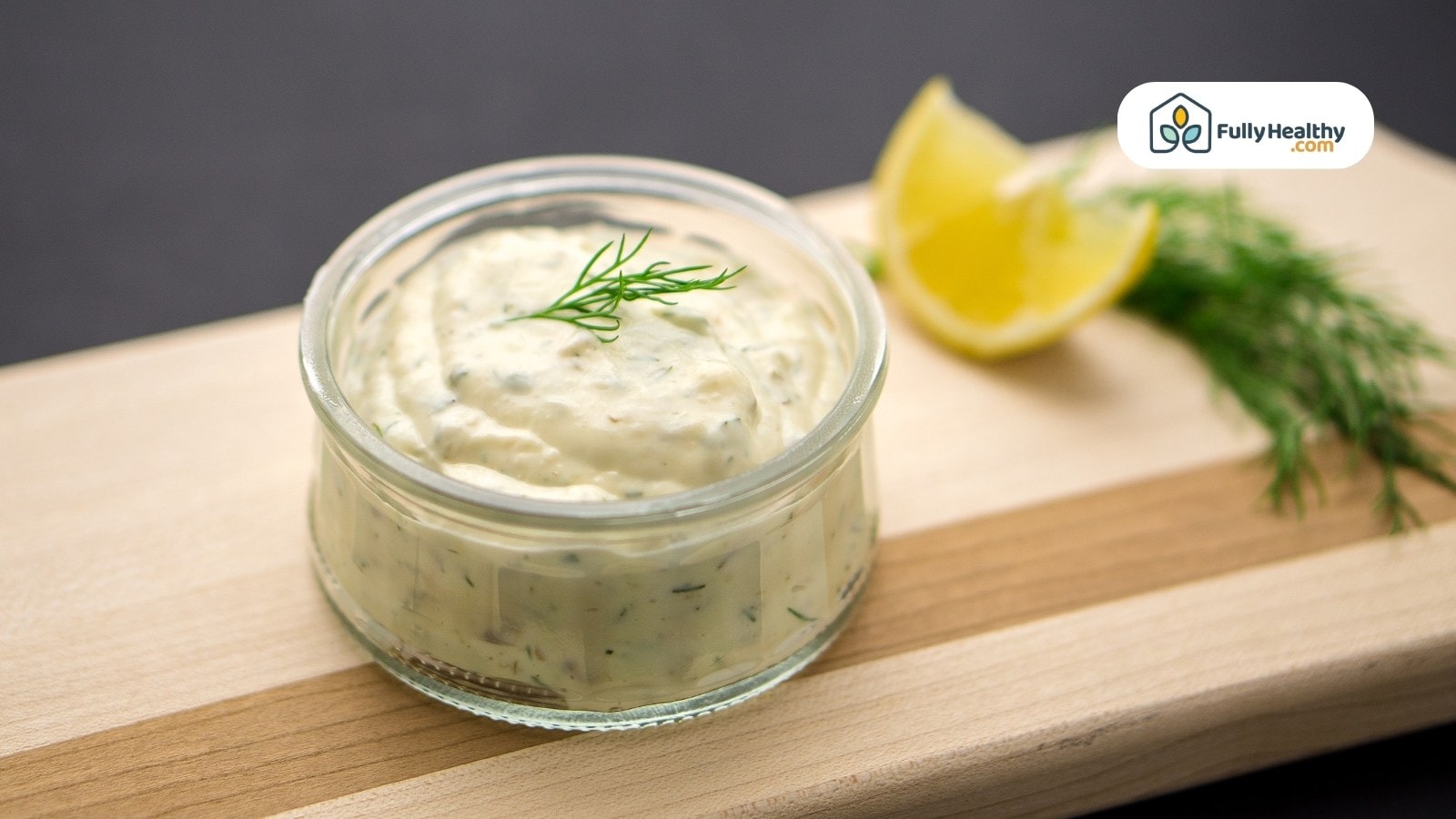 Glass jar of tartar sauce with dill and lemon wedges