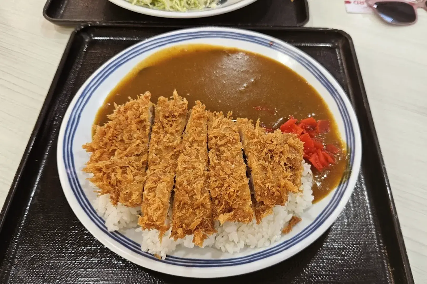 Traditional Japanese pork katsu curry featuring a crispy breaded cutlet, savory curry sauce, and fukujinzuke pickles at Maruhachi Donburi & Curry.