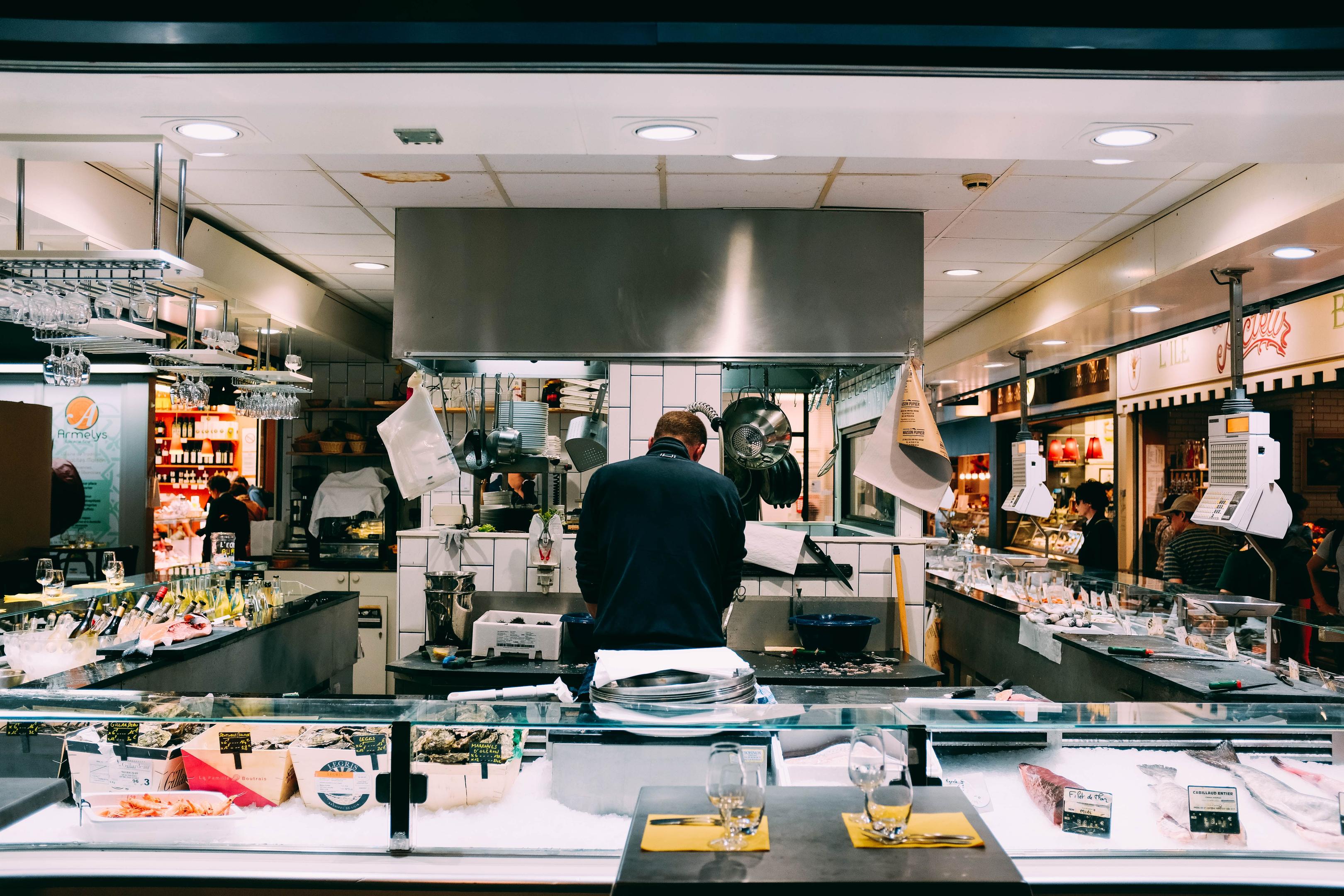 A top-down view of a commercial restaurant kitchen showcases clearly defined work zones, featuring stainless steel equipment essential for effective kitchen management and food safety. The layout emphasizes efficient kitchen operations, enabling the kitchen team to maintain high food quality and minimize food waste while ensuring a smooth workflow.