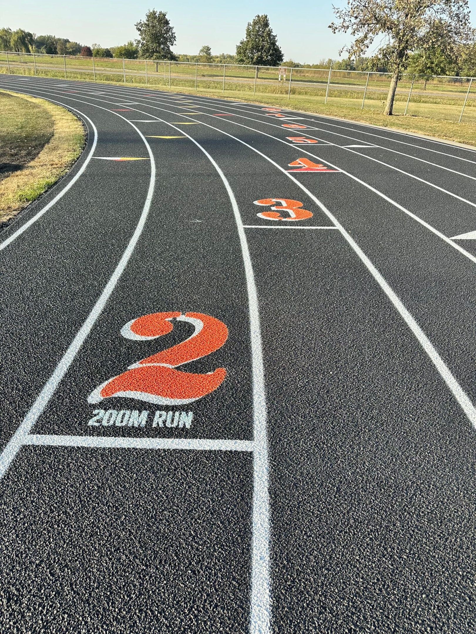 Newly resurfaced synthetic running track with lane numbers and durable textured surface.