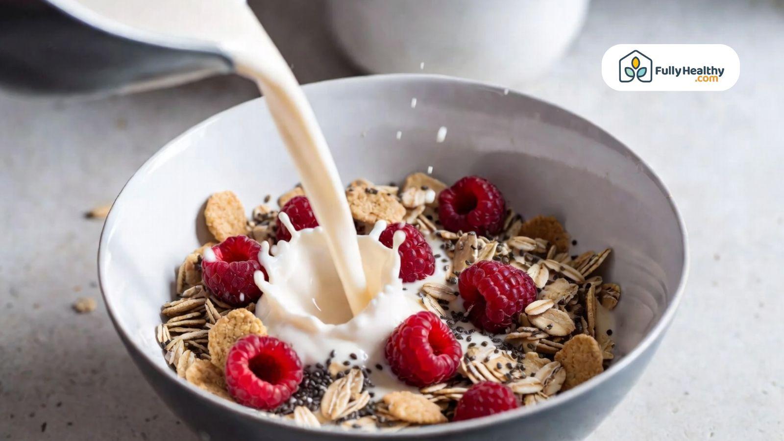 Healthy cereal breakfast with oats, raspberries, chia seeds, and milk being poured into the bowl.