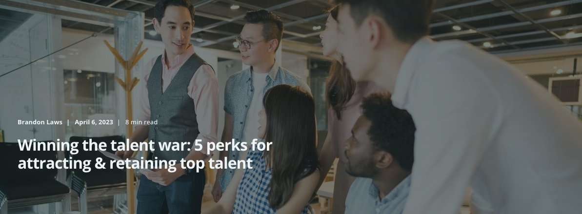 A groupd of young professionals stand by a desk discussing something. The title overlaid reads: Winning the talent war: 5 perks for attracting & retaining top talent