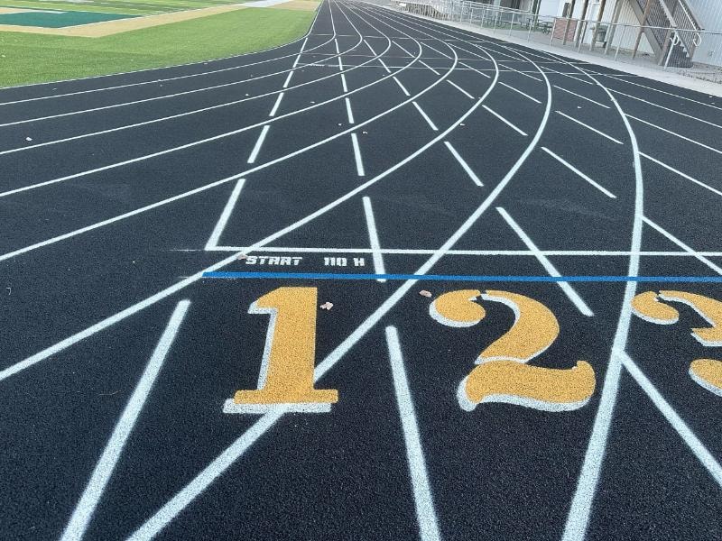 Revitalized running track at Central City High School in NE with a bold black structural spray coating, fresh lane markings, and a new school logo for a professional look.