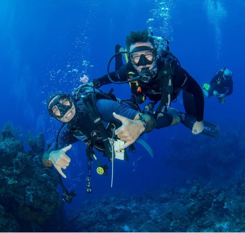 two scuba divers smiling at the camera underwater