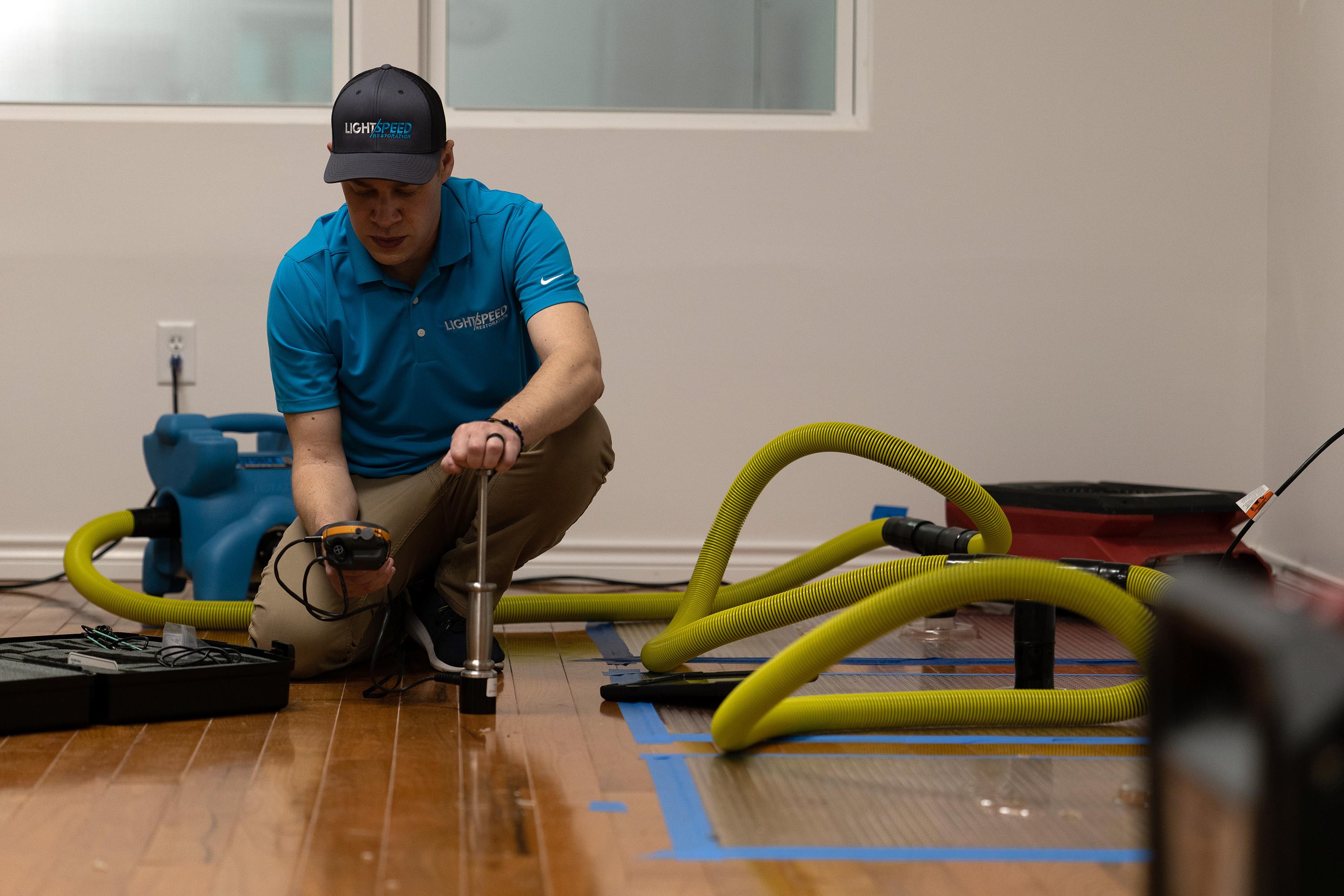 The image depicts a water-damaged living room with dehumidifiers and air movers strategically placed to aid in proper drying and prevent mold growth. Visible signs of water damage, such as sagging drywall and peeling paint, indicate the presence of hidden moisture that could lead to costly repairs and health risks if not addressed promptly.