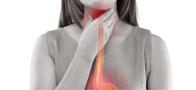 An image of a woman with the swallowing disorder achalasia touching her reddened throat. 
