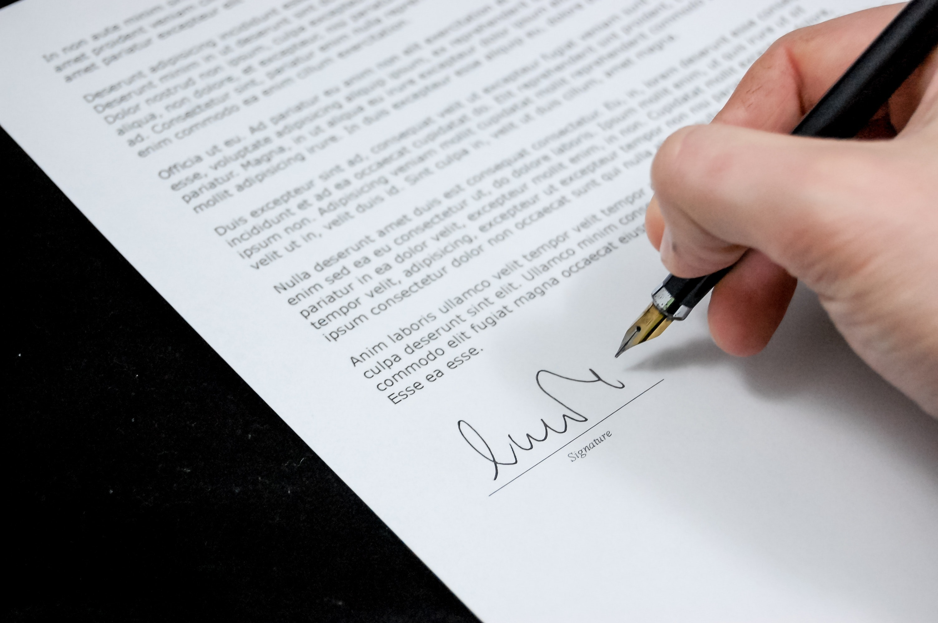 A hand signing a document