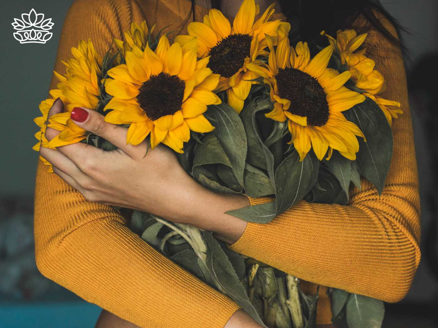 A woman in a yellow sweater cradling a bouquet of bright sunflowers, part of the Sunflowers Collection by Fabulous Flowers and Gifts. This image captures a page of autumn warmth and vivid yellow hues, highlighting the beauty of sunflower bouquets.