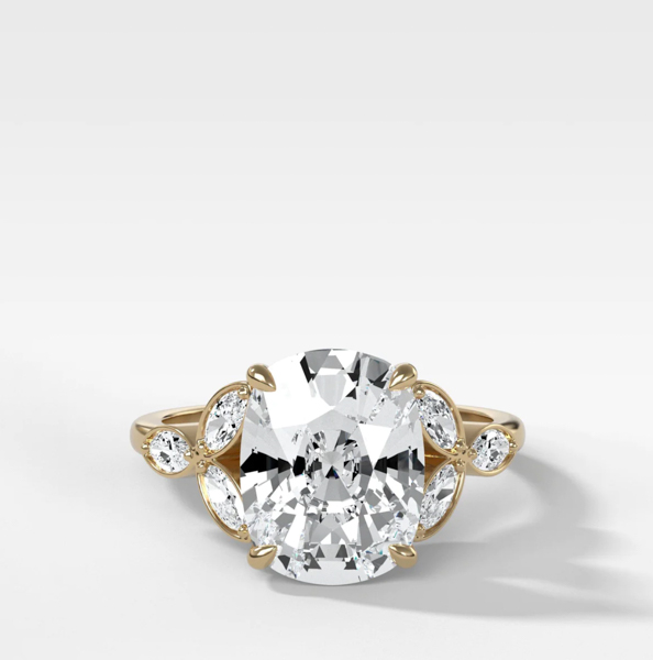 Una imagen de un anillo de inspiración vintage con una piedra central de diamante de talla cojín alargada.