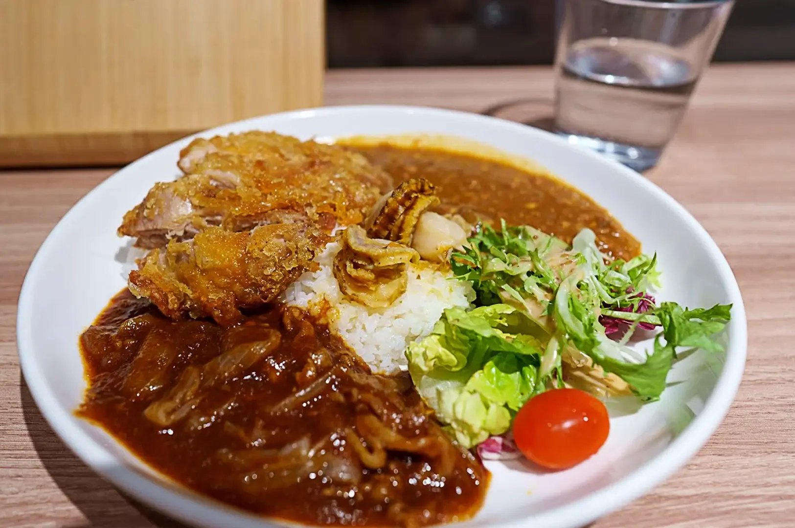 A flavorful Japanese curry set at Japan Rail Cafe in Singapore featuring breaded pork katsu, scallops, rice, and a fresh side salad.