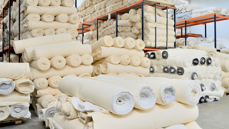 Many rolls of fabric are stacked in a warehouse