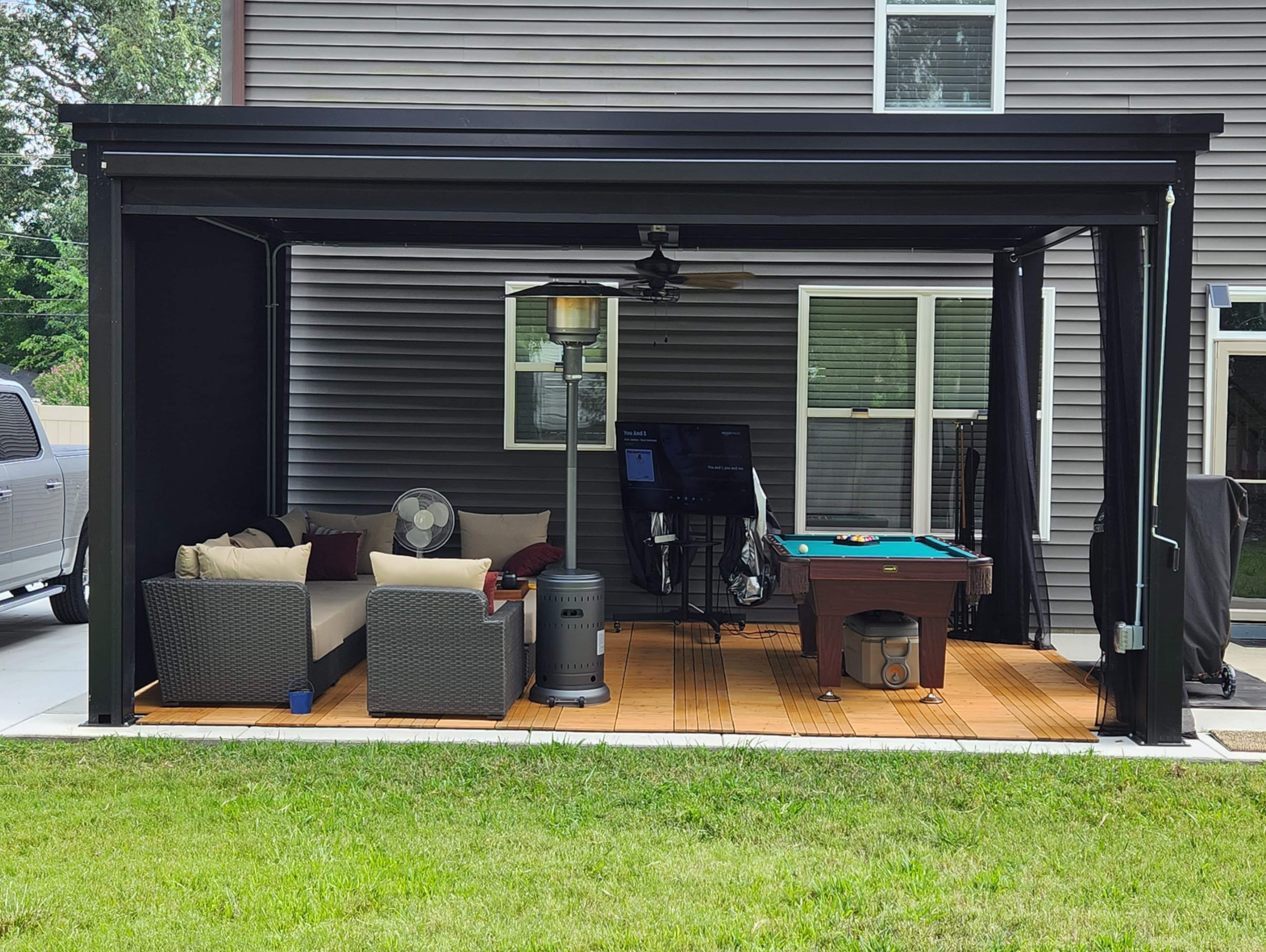 Outdoor living room with outdoor seating, pool table, and a luxury pergola.