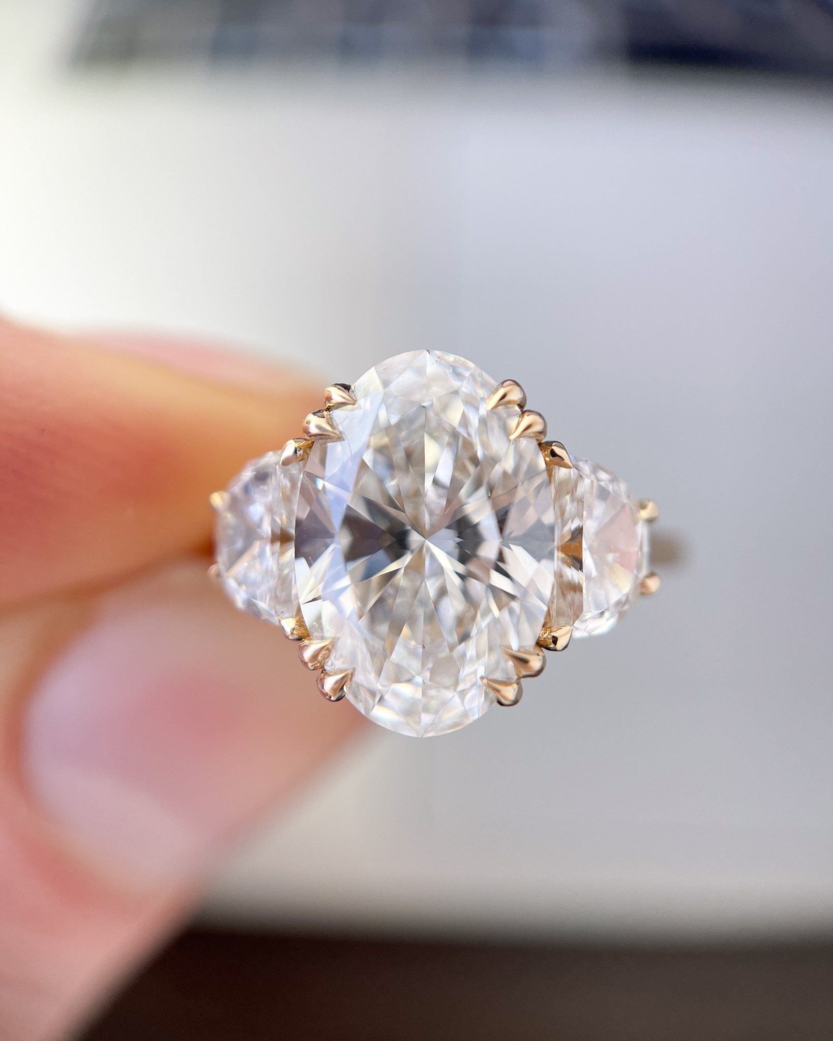 Un anillo de compromiso de tres piedras con un centro de diamantes ovalados y piedras laterales en forma de media luna.
