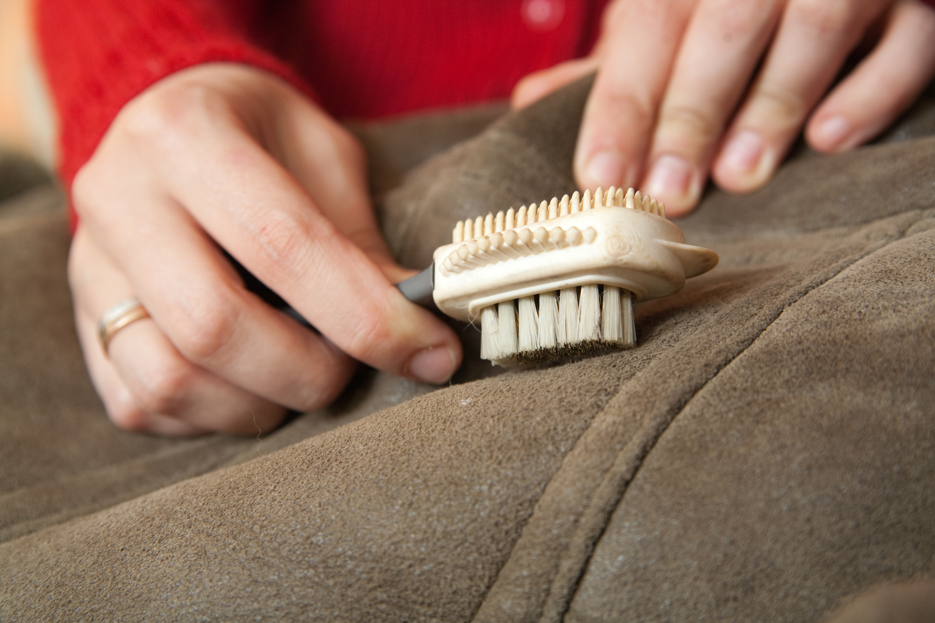 A person using a soft brush to clean leather furniture