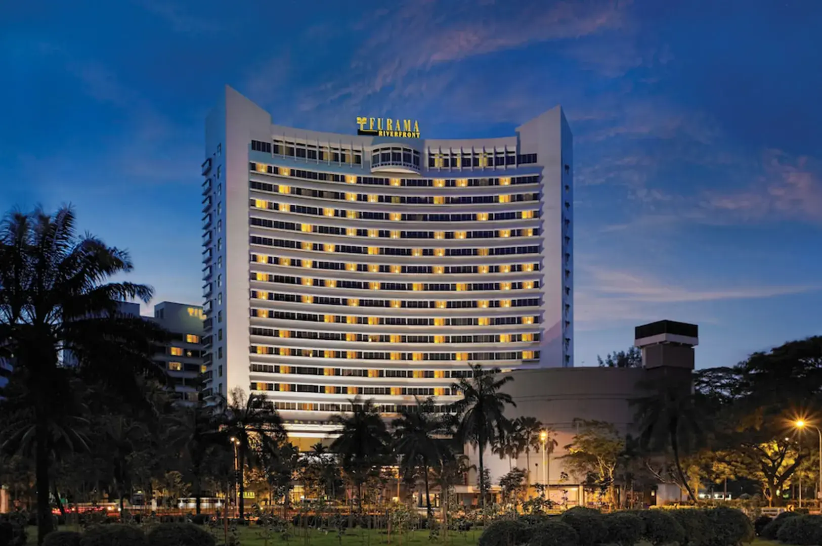 Furama RiverFront Singapore hotel at dusk with illuminated facade.