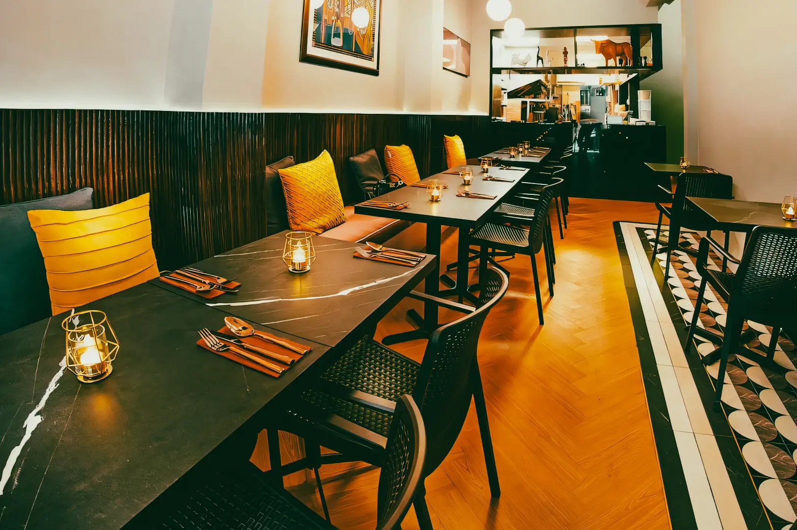 Wide-angle shot of a modern halal restaurant interior with black tables, yellow cushion seating, candlelight accents, and a cozy upscale dining atmosphere.
