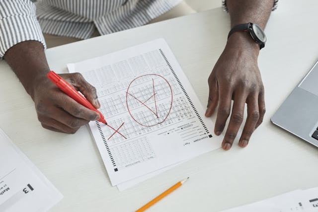 Teacher seated at a desk grading a test