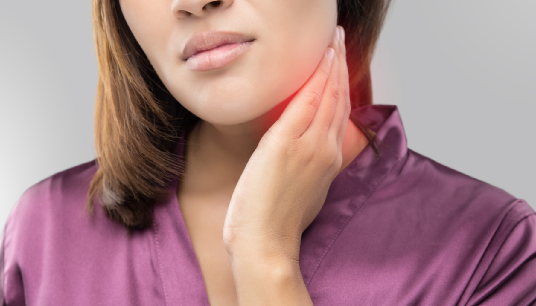 Lymfeknuter: Når Du Bør Være Bekymret for Hevelser i Halsen 12 Kvinne holder seg på halsen med smerteuttrykk, antyder hevelse eller ubehag i lymfeknuter eller svelg.