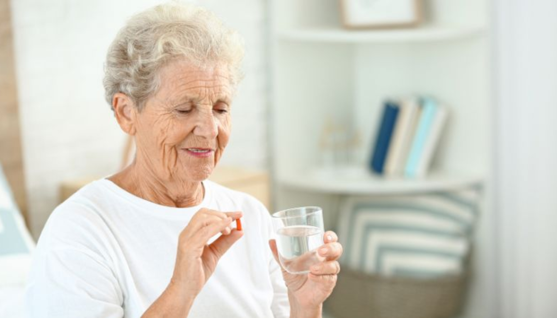 Trekke tann på blodfortynnende – Viktig å vite før inngrepet 10 Eldre kvinne holder et glass vann og en pille, klar til å ta medisinen.