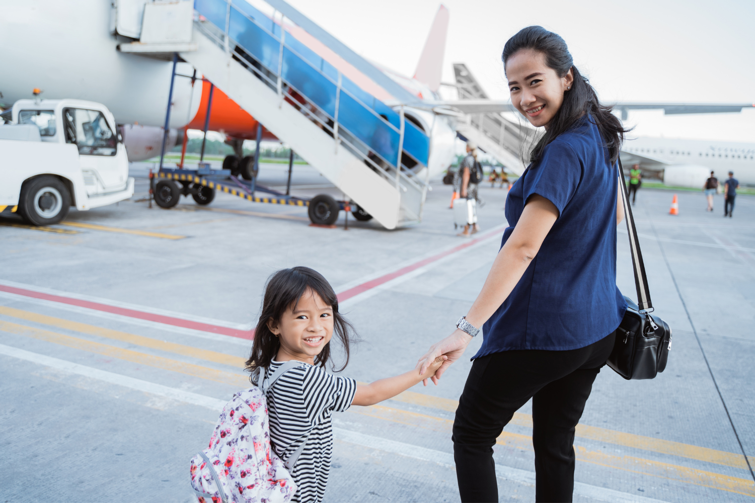 a mother and daughter walking towards the flight