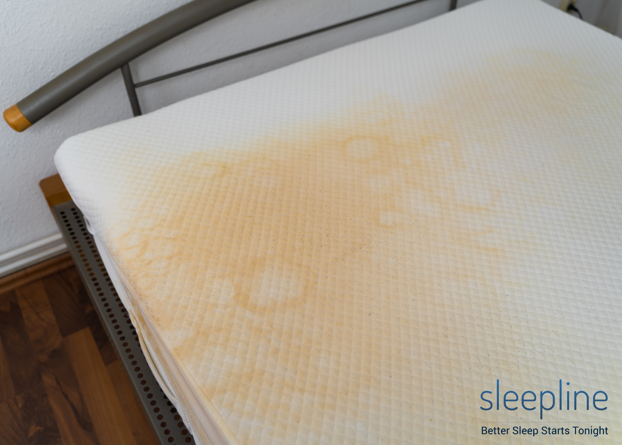 A yellow-stained mattress in a bedroom