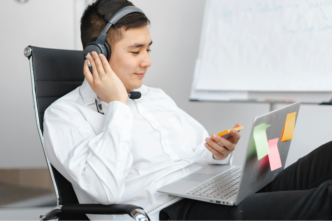Remote Filipino employee using headphones and laptop while reviewing work tasks in a flexible home setup
