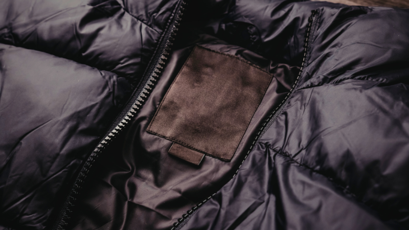 Close-up of a black gorpcore jacket with a zipper and a blank tag.