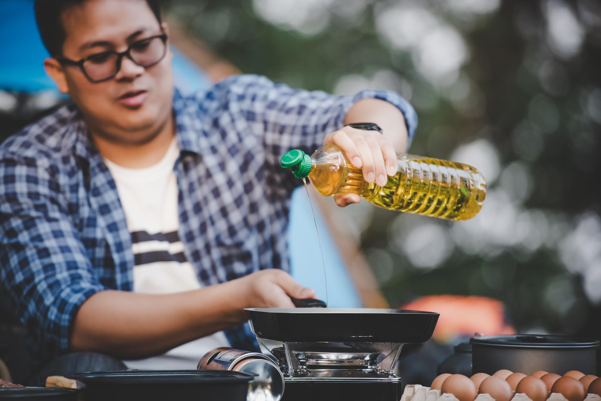 A man pouring cooking oil in a pan
