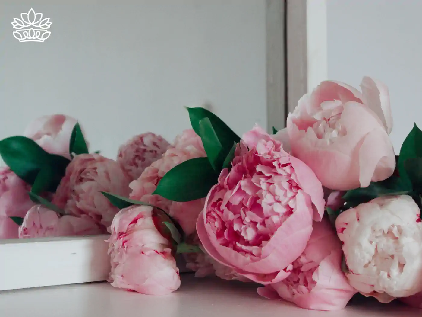A delicate arrangement of pink peonies placed on a white surface. Fabulous Flowers and Gifts - Peonies Collection