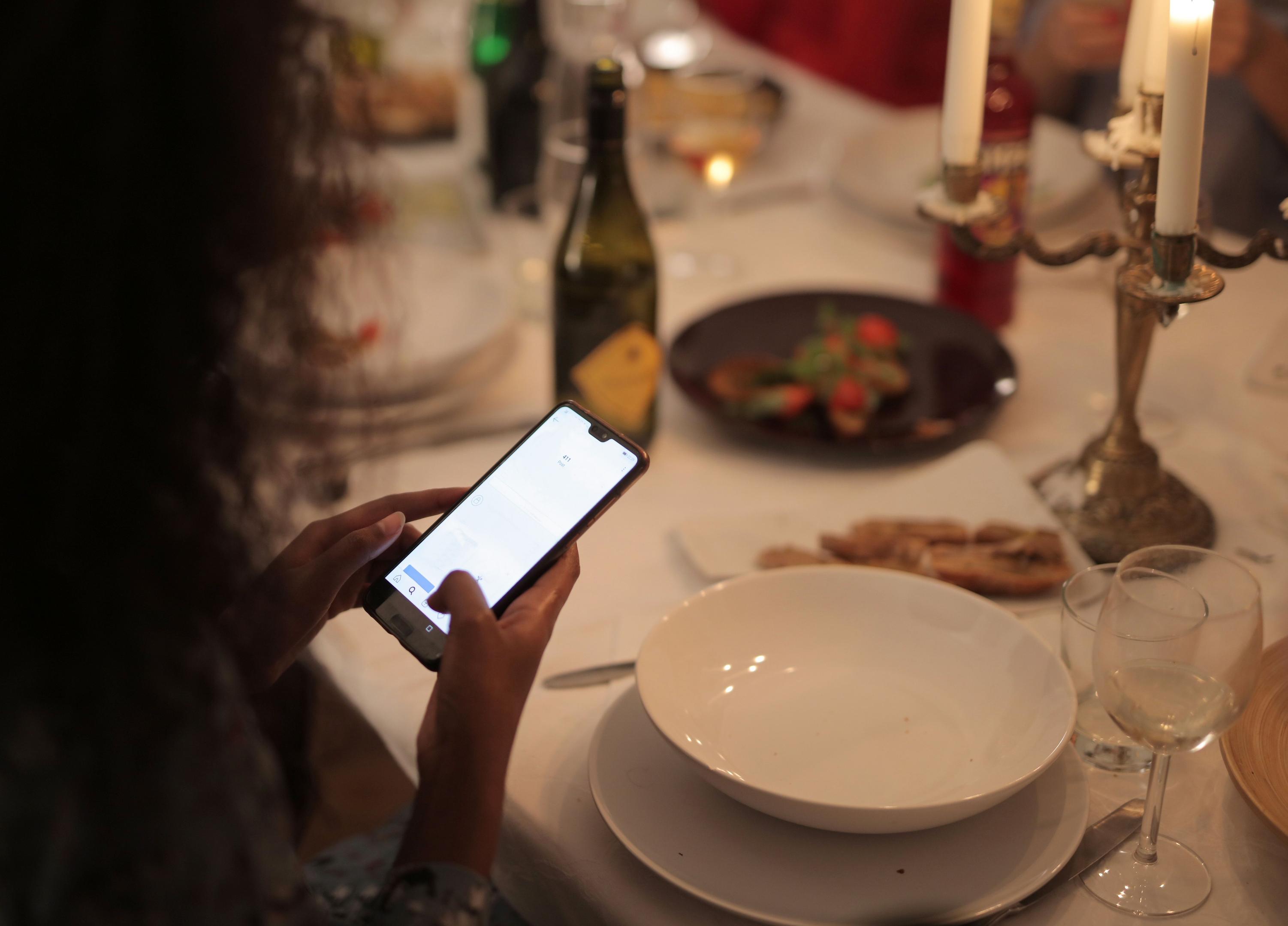 A chef is meticulously arranging a vibrant dish on a plate, showcasing colorful ingredients, while another person captures the moment with a smartphone, likely for social media marketing to attract new customers and enhance the restaurant's digital presence. This scene highlights the importance of high-quality photos in restaurant marketing to engage customers and build loyalty.
