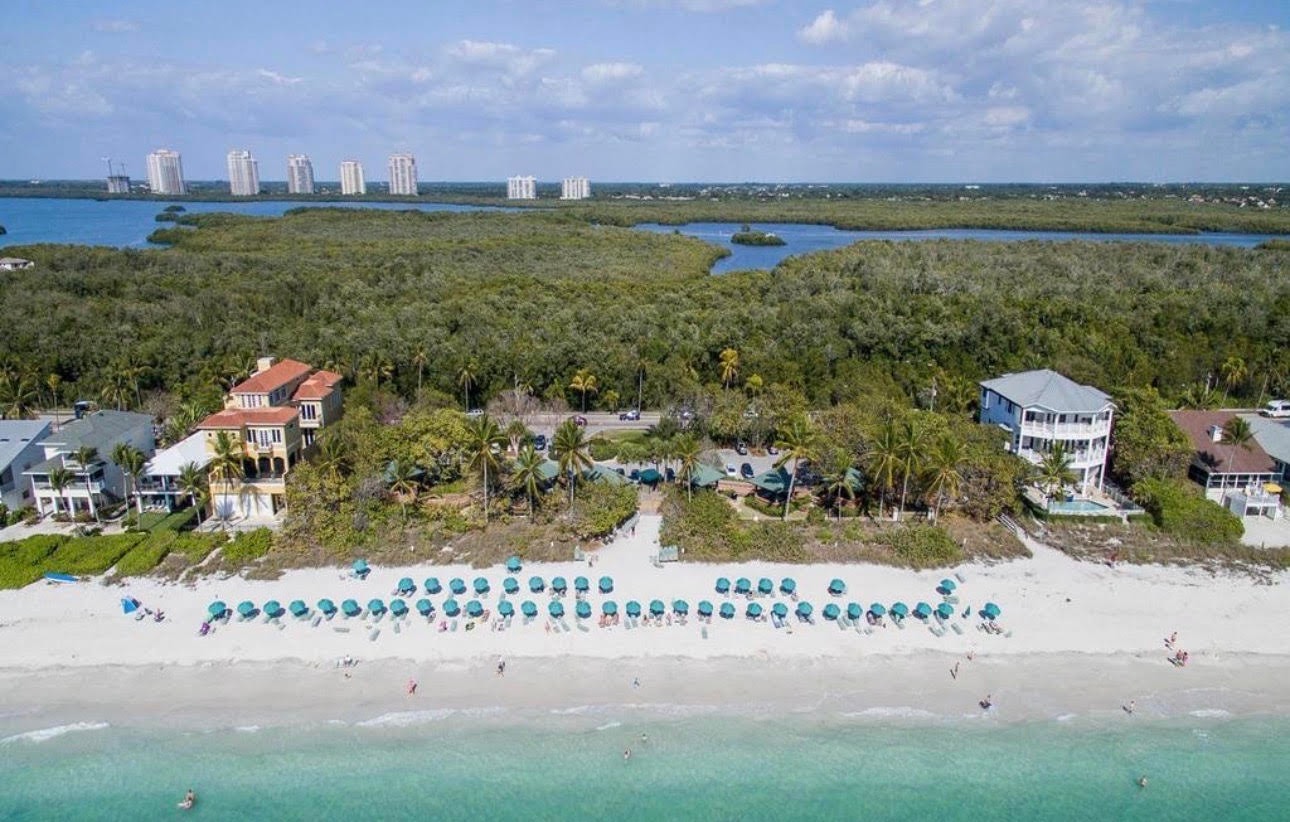 The image depicts a modern beach club facility featuring spacious outdoor seating areas with stunning views of the Gulf. This private beach club in Bonita Springs offers resort-style amenities, perfect for enjoying the natural beauty and breathtaking sunsets of Southwest Florida.