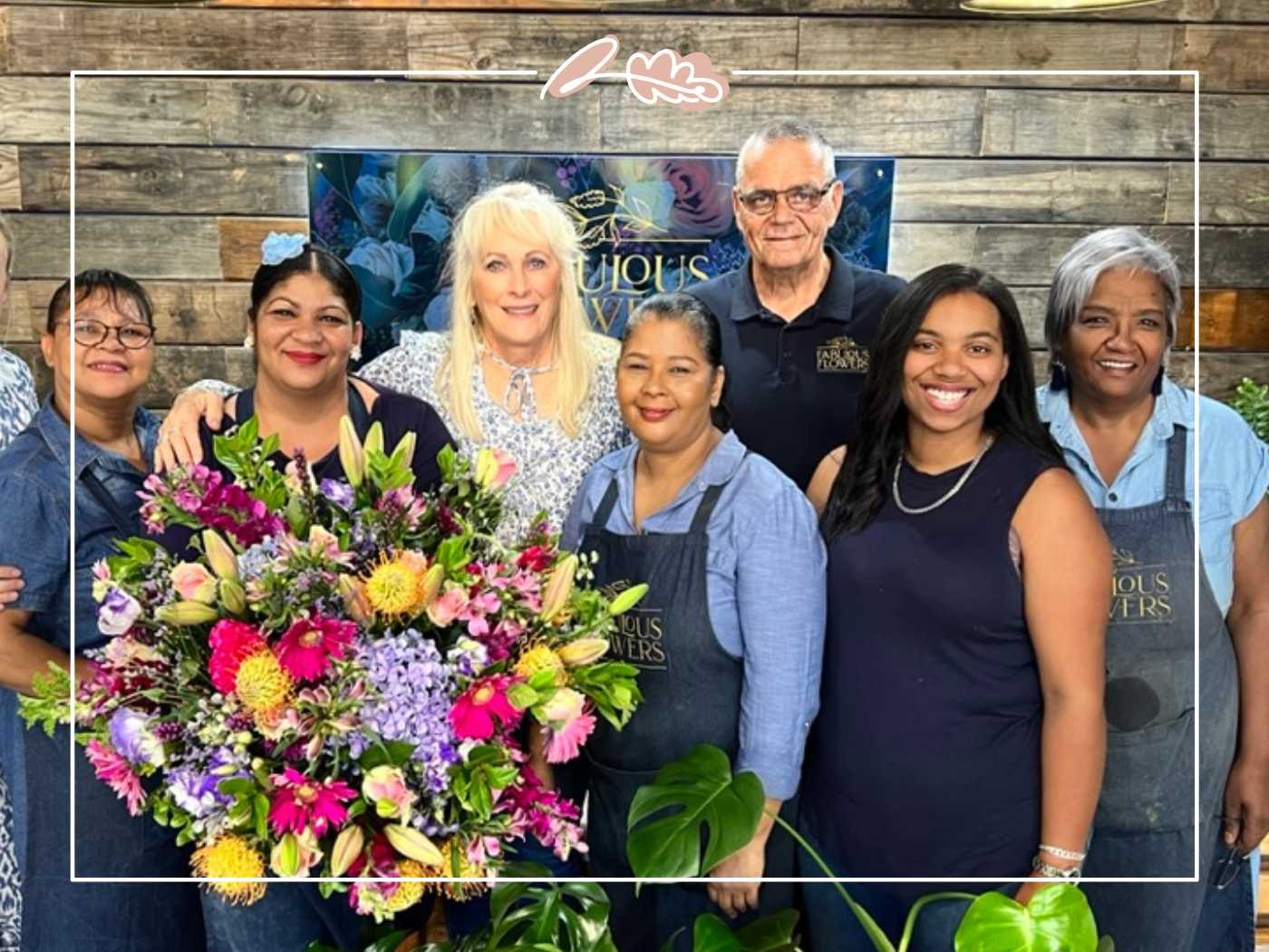 Group of people smiling and holding a large bouquet of flowers - Fabulous Flowers and Gifts