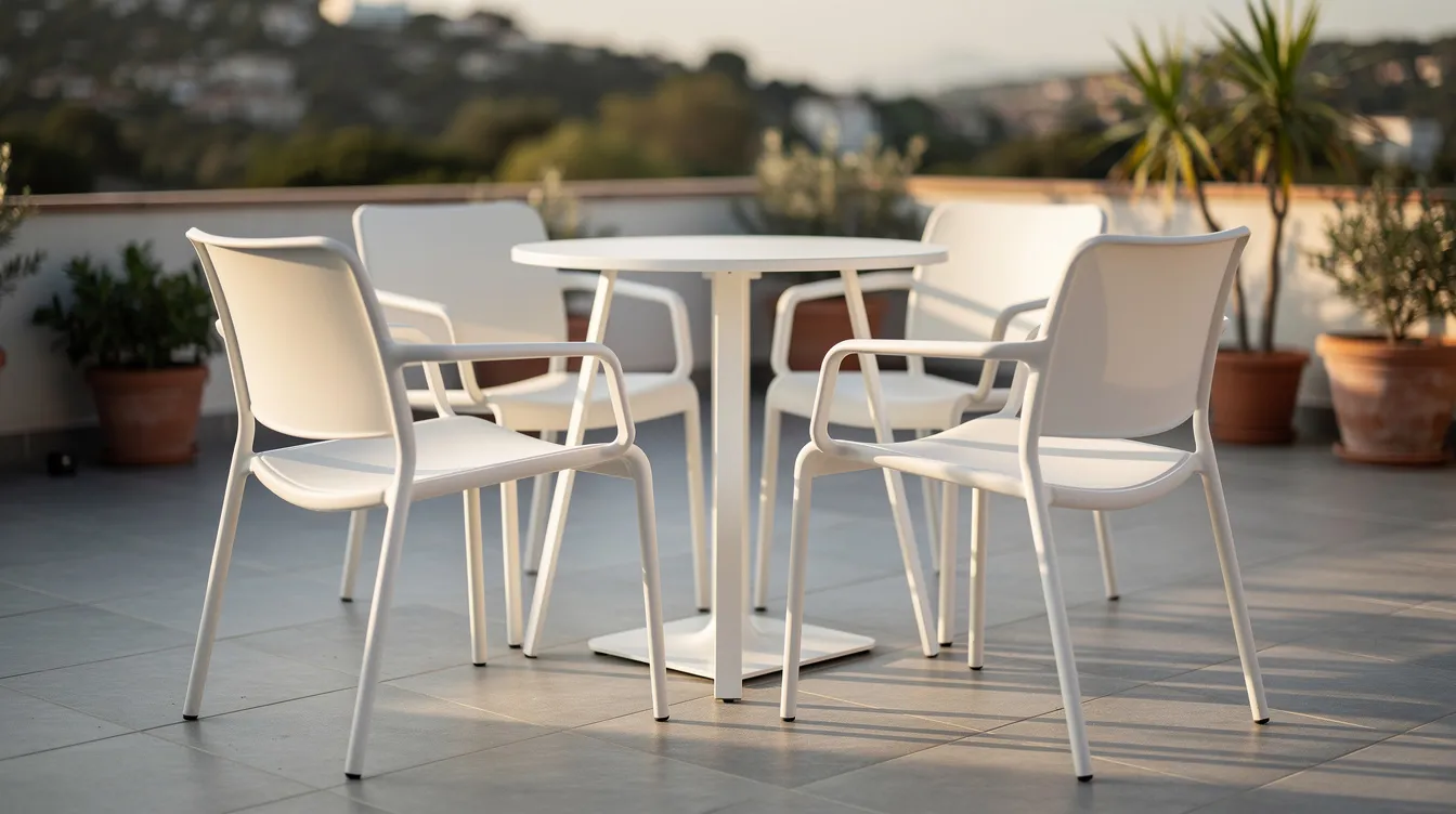 En terrass med vita stapelbara italienska utestolar i modern design står i fokus, tillsammans med ett litet cafébord. Denna italienska inredning erbjuder både stil och funktionalitet, perfekt för avkoppling utomhus.