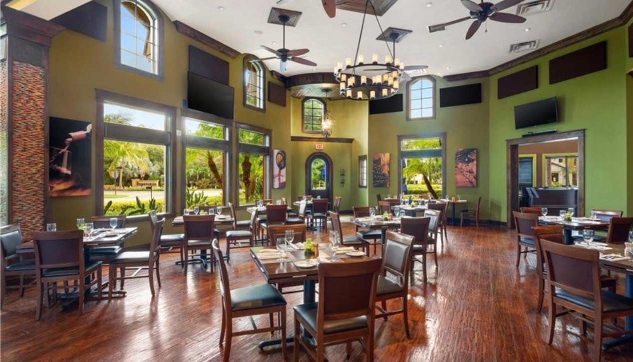 The image depicts a community gathering area in the prestigious Paseo community of Fort Myers, where residents are engaged in various outdoor activities, showcasing the vibrant resort-style living and incredible amenities that this award-winning community offers. The scene captures the essence of community spirit amidst the beautiful surroundings of South Fort Myers.