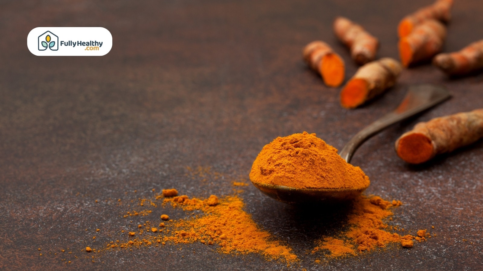 Spoonful of turmeric powder with sliced turmeric roots in background