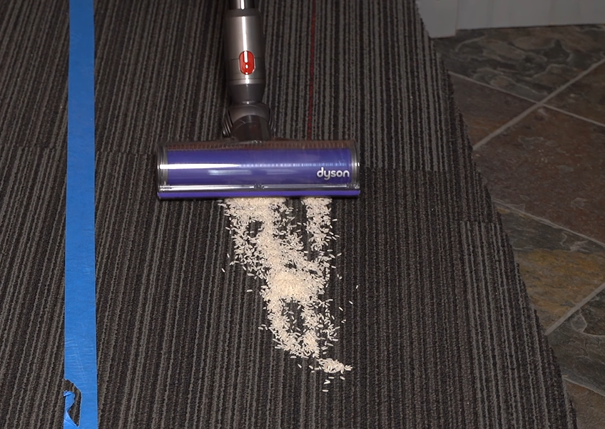 Dyson V8 cordless vacuum picking up rice on carpet