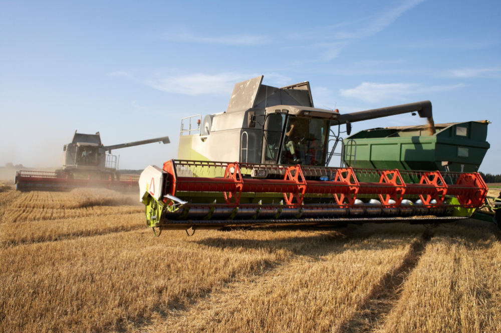 A large green and red combine harvester parked on a construction site, showcasing its robust design and functionality.