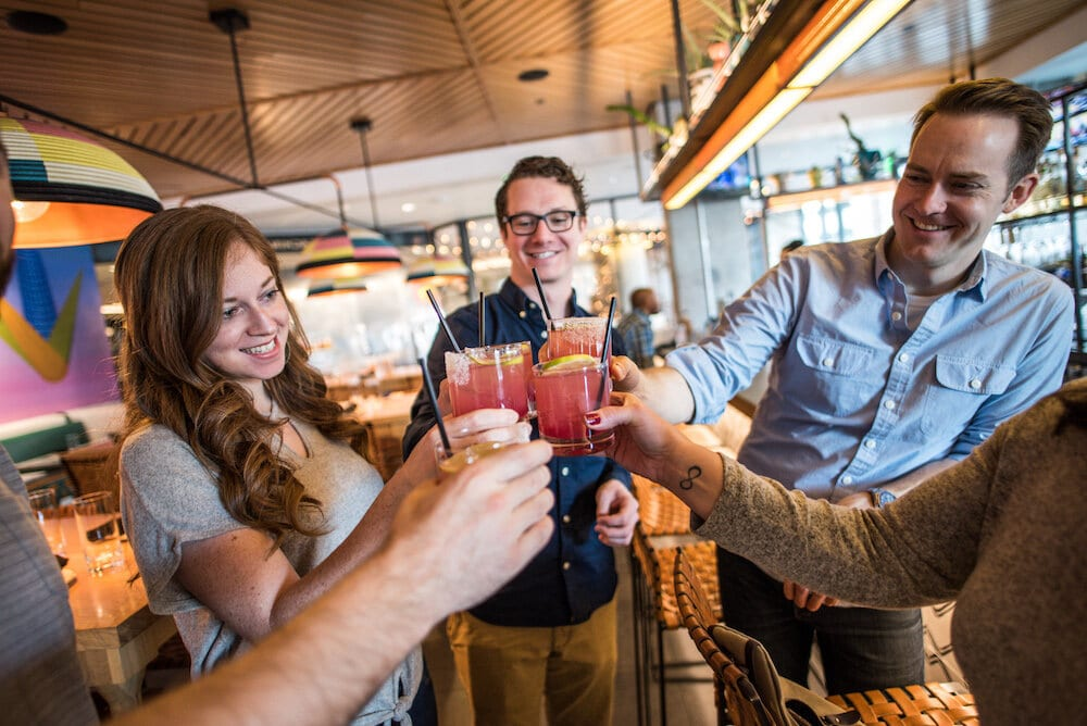 A group clinking glasses on a cocktails + tastes tour by Delicious Denver Food Tours