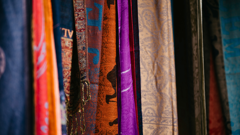 A bunch of colorful trendy scarves hanging on a rack