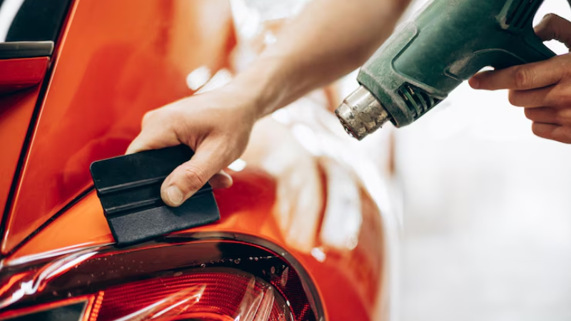 A mechanic using heat gun to apply smoothly PPF without paint damage