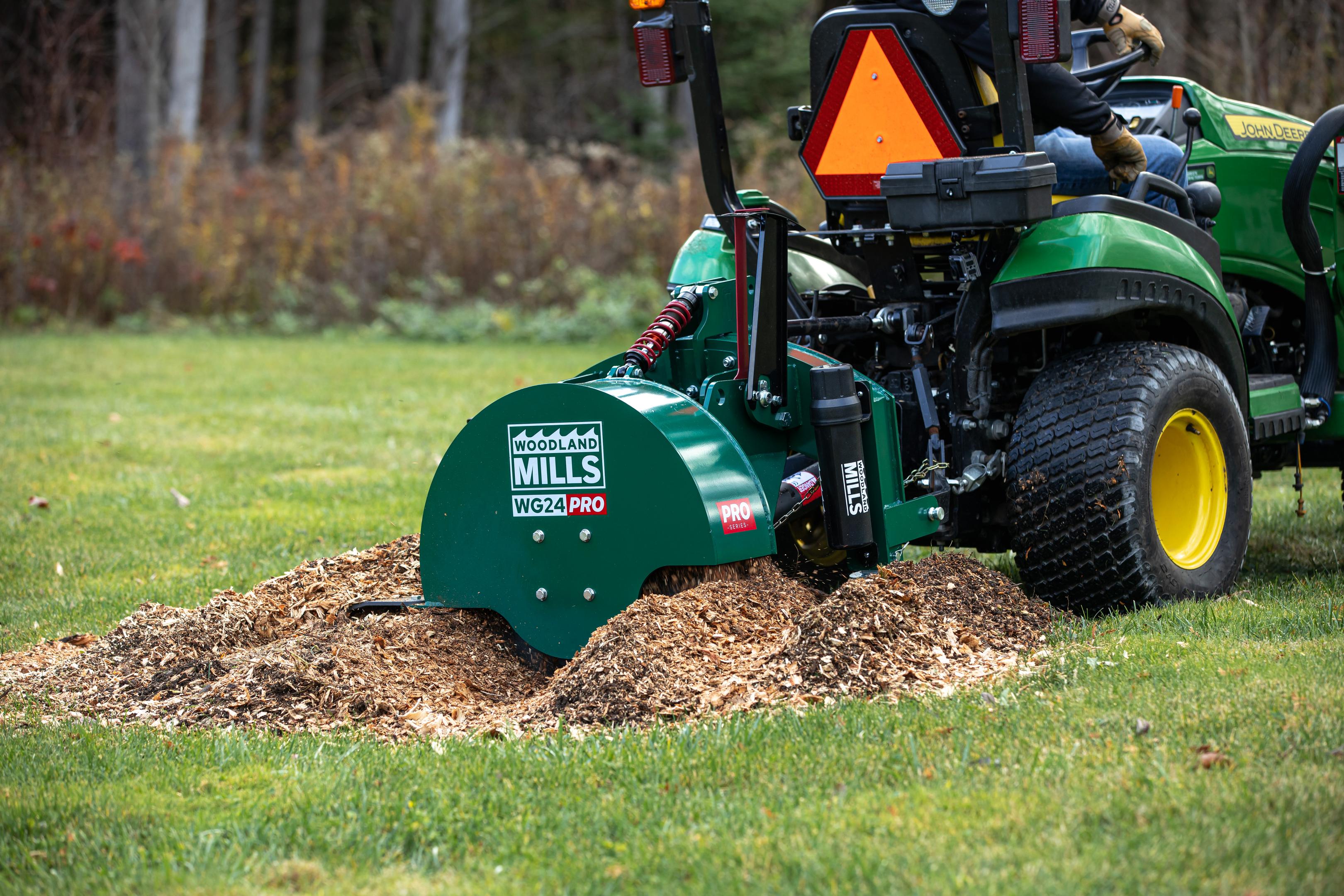 A Woodland Mils WG24 PRO Stump Grinder attached to a tractor grinding a stump.