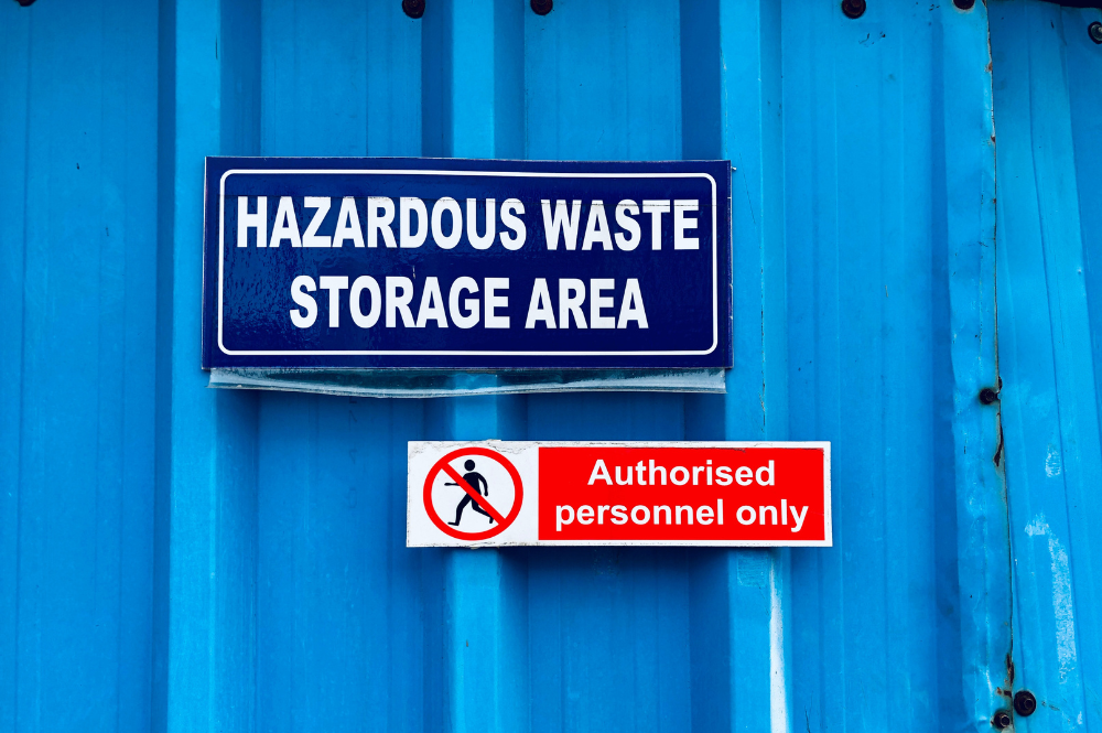 A blue wall with a prominently placed sign outlining safe practices for hazardous waste disposal.
