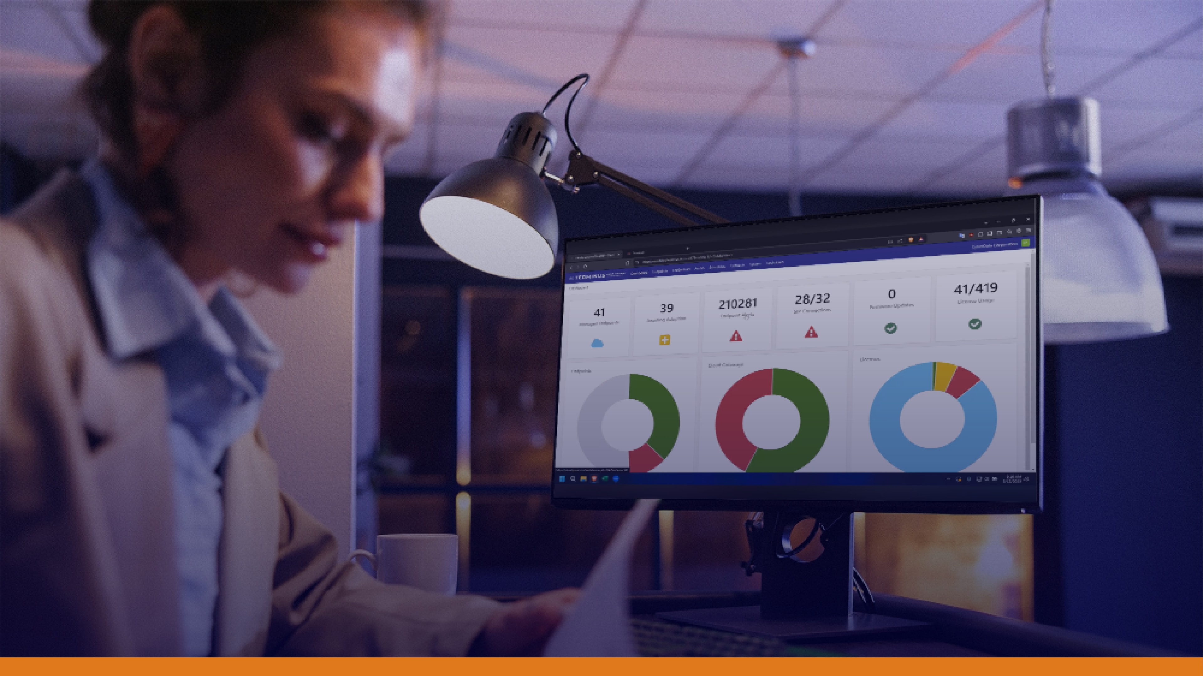 Woman working late at a desk while monitoring charts on a screen, representing the importance of delivering emergency messages during severe weather events to maintain workplace safety.
