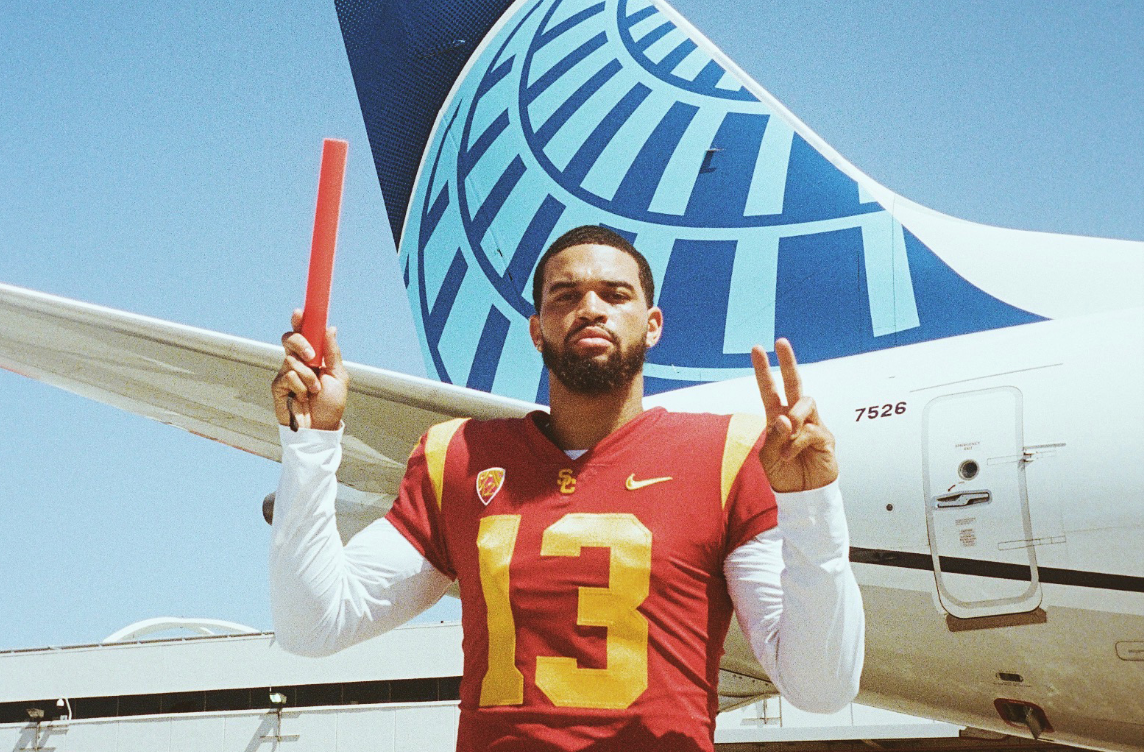 USC quarterback Caleb Williams in full uniform posing confidently in front of a United Airlines plane, representing his high-profile NIL deal with the airline.