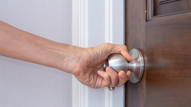 Hand opening a door with a knob