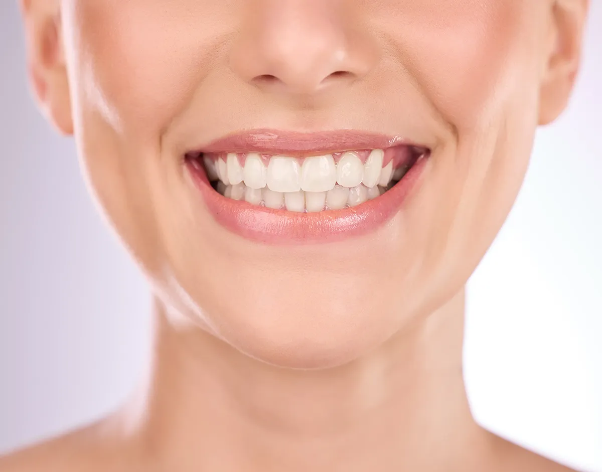 Close-up of a bright, healthy smile displaying perfectly aligned white teeth against a light background, showcasing optimal dental aesthetics. Retry