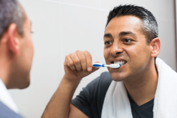 man gently brushing teeth following after surgery care instructions